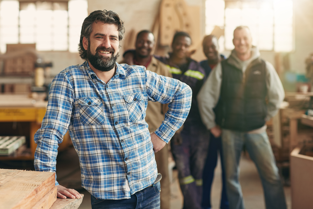 person smiles for camera in foreground of workshop