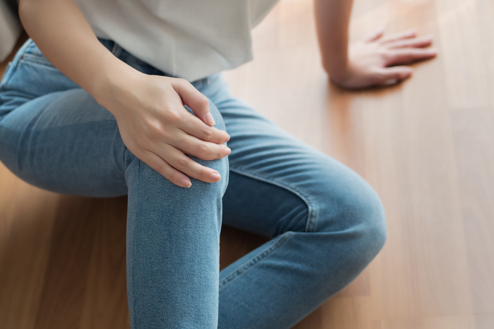 Person sits on floor while grasping knee